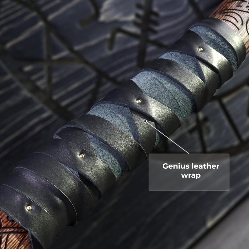 May include: Close-up of a wooden handle with a black leather wrap. The leather is wrapped in a spiral pattern and secured with small metal studs. The text "Genius leather wrap" is visible.