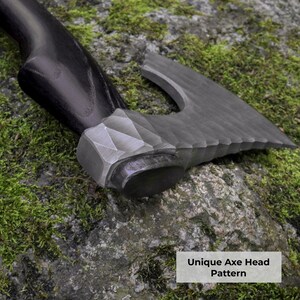 May include: A hand axe with a dark, smooth wooden handle and a textured, metallic axe head featuring a faceted, geometric pattern near the connection point. The blade has a dark, matte finish with a distinct, serrated-like edge design.