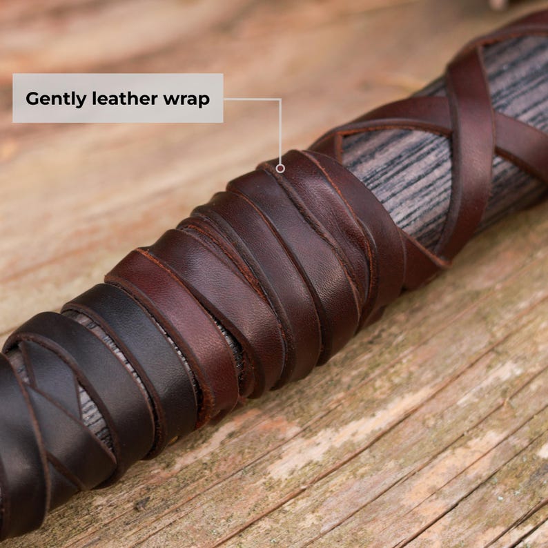 May include: Close-up of a wooden handle wrapped in dark brown and black leather. The leather is intricately woven and appears to be hand-stitched. The text "Gently leather wrap" is in the image.
