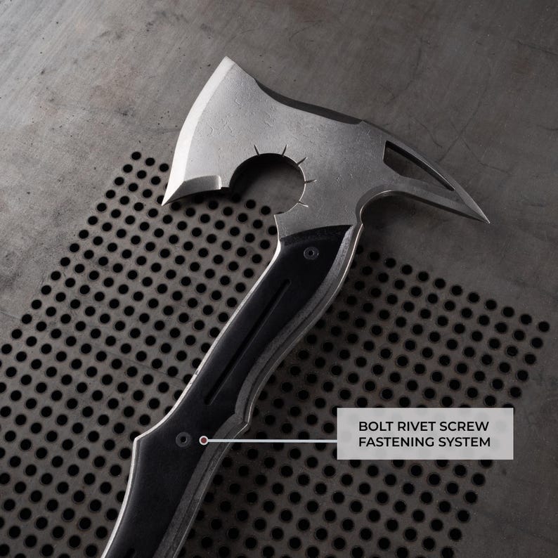 Puede incluir: Un hacha plateada y negra con una hoja curva y un extremo puntiagudo. El mango es negro con un agarre texturizado. El texto "BOLT RIVET SCREW FASTENING SYSTEM" es visible.