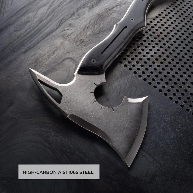 Puede incluir: Un hacha de acero con alto contenido de carbono con un mango negro y un dise&ntilde;o de hoja &uacute;nico. El cabezal del hacha presenta un recorte circular y un filo afilado. El texto "HIGH-CARBON AISI 1065 STEEL" est&aacute; visible.