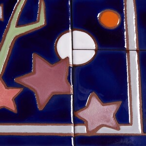 May include: A close-up of a blue ceramic tile with a white, orange, and pink star design. The tile has a white border and a green stem design.
