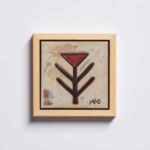 Puede incluir: Un azulejo de cerámica enmarcado con un diseño de árbol estilizado en negro y rojo sobre un fondo beige. El azulejo está firmado "AAB" en la esquina inferior derecha.