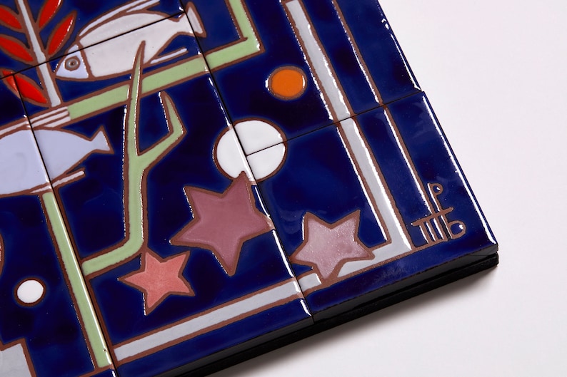 May include: A close-up of a blue and white ceramic tile with a geometric design featuring stars, fish, and a branch. The tile is signed with the initials "LF" in the lower right corner.