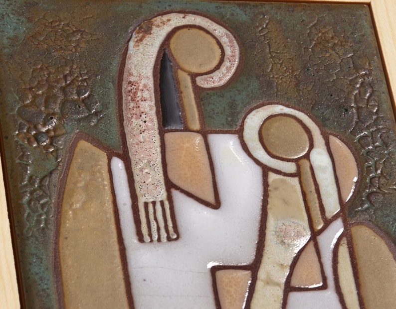May include: A ceramic tile with a stylized design of two figures. The figures are outlined in brown and have a white background. The tile has a textured, brown background.