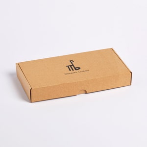 May include: A brown cardboard box with the text "Valimaki Caramels" and a logo of a stylized "MB" printed on the top.