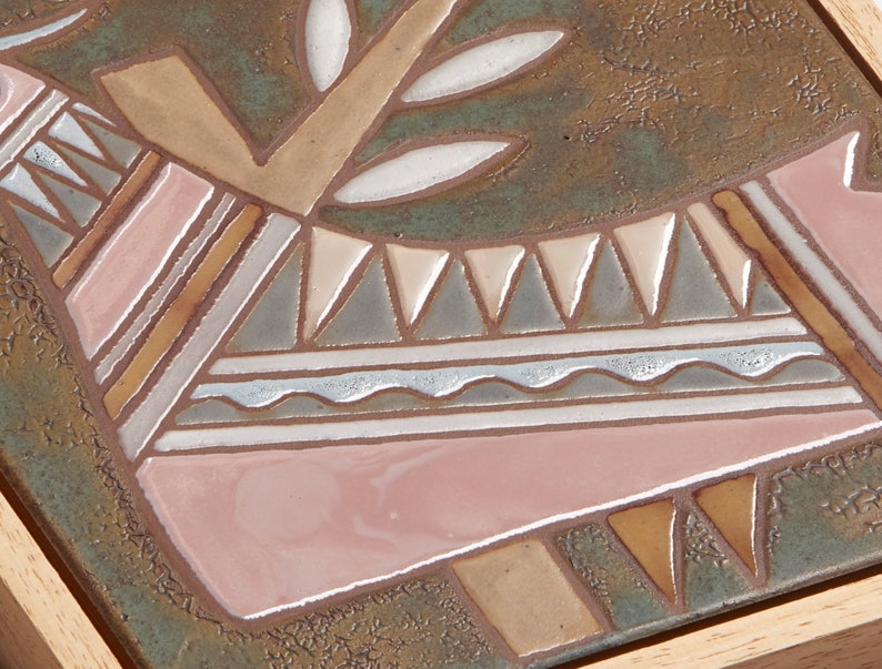May include: A ceramic tile with a geometric design in shades of brown, pink, white, and gray. The design features a stylized animal with a tree growing from its back.