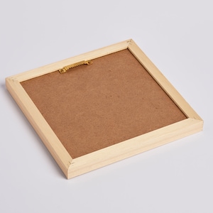 May include: A wooden picture frame with a brown cardboard backing. The frame has a gold-colored hanging hook on the back.