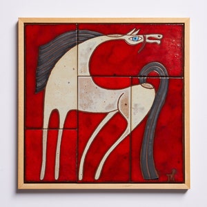 Puede incluir: Un mural de azulejos de cerámica enmarcado que representa un caballo blanco con una crin y una cola negras sobre un fondo rojo.