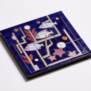May include: A blue ceramic tile with a design of three white fish swimming in a blue and green underwater scene with red and orange coral and pink and white stars. The tile is made up of nine smaller tiles.