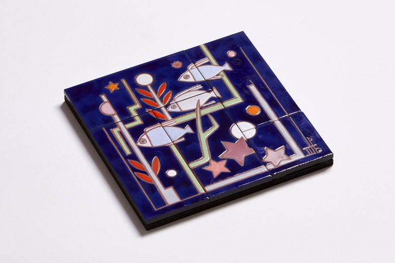 May include: A blue ceramic tile with a design of three white fish swimming in a blue and green underwater scene with red and orange coral and pink and white stars. The tile is made up of nine smaller tiles.