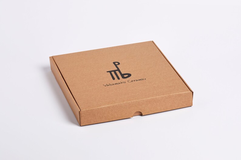 May include: A square, brown cardboard box with a lid. The box has a black logo and text that reads "Valiamaki Ceramics". The box is on a white background.