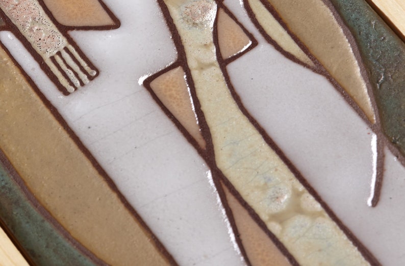 May include: Close-up of a ceramic tile with a geometric design in shades of brown, beige, and white. The tile has a textured surface and a glossy finish.
