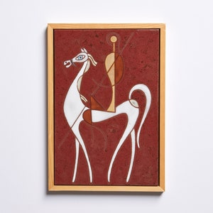 Puede incluir: Un azulejo de cerámica enmarcado con un diseño geométrico blanco de un caballo y un jinete sobre un fondo rojo.