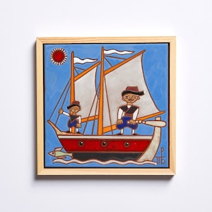 May include: A framed ceramic tile with a blue background depicting a red sailboat with two figures on board. The sailboat has two white sails and a yellow mast. The figures are wearing blue and red clothing and hats. The tile is framed in wood and has a red sun in the upper left corner.