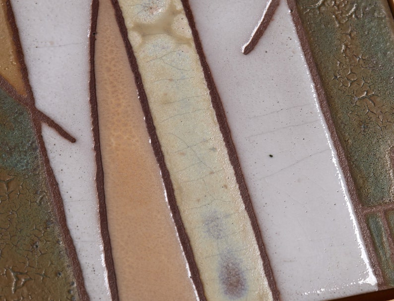 May include: Close-up of a ceramic tile with a brown, white, and beige design. The tile has a textured surface and a crackled glaze.