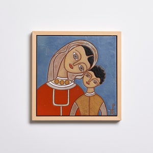 Puede incluir: Un azulejo de cerámica enmarcado con una pintura de una mujer y un niño. La mujer lleva un vestido rojo y una cubierta de cabeza blanca. El niño lleva una camisa marrón. El fondo es azul.