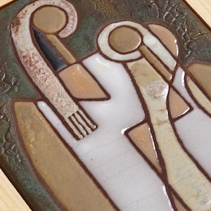 May include: A ceramic wall tile with a geometric design in shades of brown, beige, and white. The tile is framed in wood.