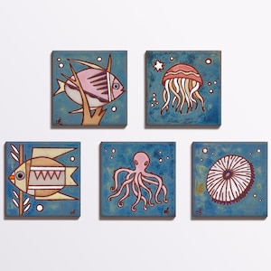 May include: Five ceramic tiles with blue backgrounds and white dots. Each tile features a different sea creature: a pink fish, a red jellyfish, a pink octopus, a white sea urchin, and a yellow fish.