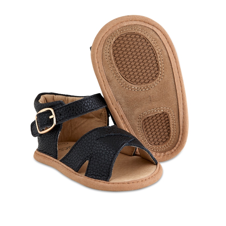 May include: Black leather baby sandals with a buckle fastening and a brown sole.