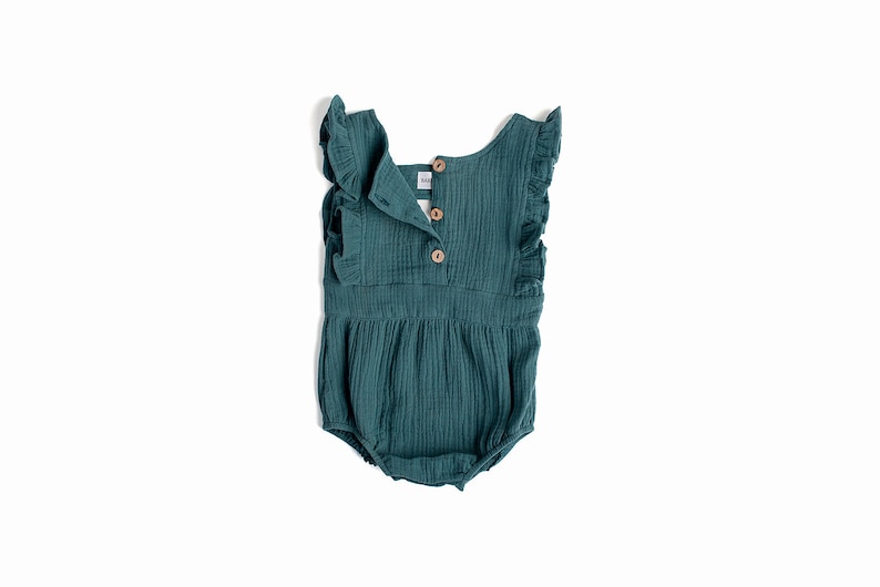 May include: A teal blue baby onesie with ruffled sleeves and a button closure in the back. The onesie is made of a soft, textured fabric.