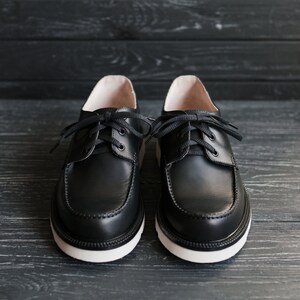Peut inclure: Une paire de chaussures en cuir noir &agrave; lacets avec des semelles blanches. Les chaussures ont un design classique et sont faites de cuir de haute qualit&eacute;.