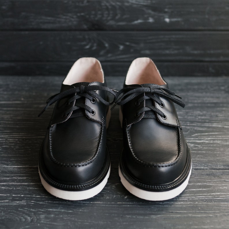 Peut inclure: Une paire de chaussures en cuir noir &agrave; lacets avec des semelles blanches. Les chaussures ont un design classique et sont faites de cuir de haute qualit&eacute;.