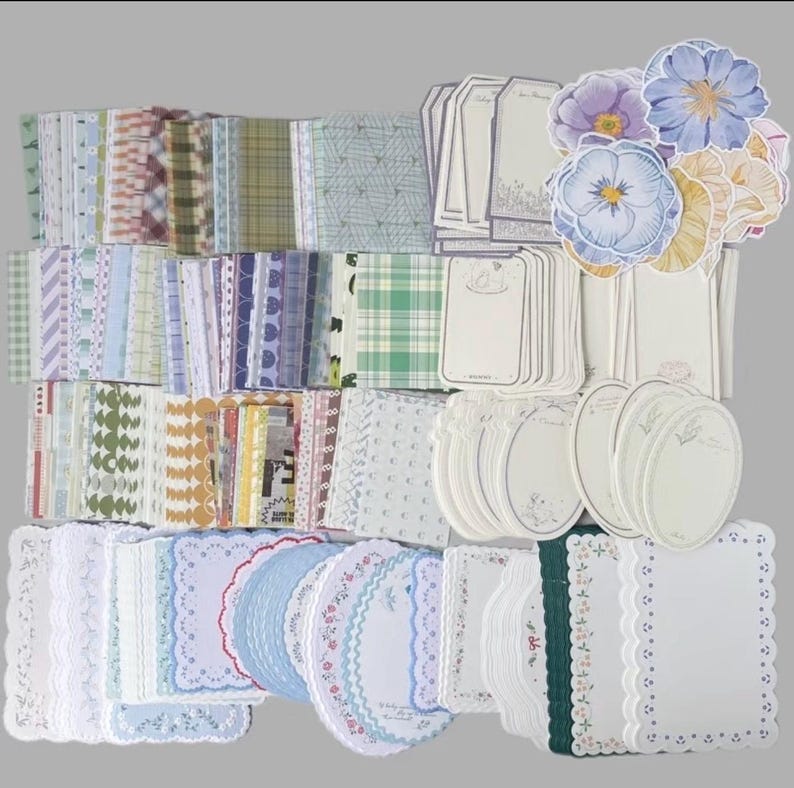 May include: A collection of decorative paper items, including patterned sheets, tags, and stickers. The sheets feature various designs, such as floral, plaid, and geometric patterns. The color palette includes pastel shades of blue, green, pink, and white, with floral stickers.