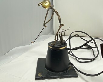 May include: A wire sculpture of a golfer swinging a club with a glass ball for a head. The sculpture is mounted on a black base with a cord and plug. The base is labeled "3rd Shot".