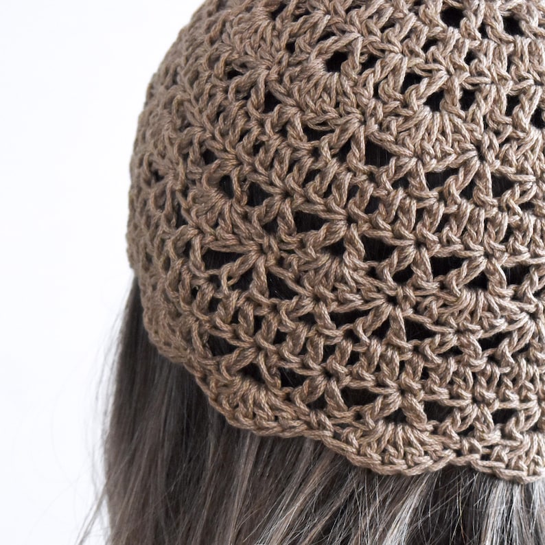 Puede incluir: Un gorro de ganchillo marr&oacute;n con un intrincado patr&oacute;n de estrellas caladas repetitivas. La prenda est&aacute; confeccionada con hilo de textura visible y presenta un borde festoneado en el dobladillo inferior que descansa sobre cabello oscuro.