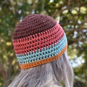 May include: A brown, red, teal, and orange crocheted beanie hat.