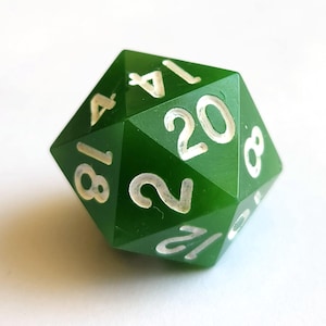 May include: A green, twenty-sided die with white numbering. The die is a deep emerald green color and is designed for tabletop role-playing games. The numbers are clearly visible, making it easy to read the results of a roll.