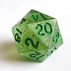 May include: A green twenty-sided die with glitter embedded in the plastic. The numbers 1, 4, 8, 12, 16, 20 are visible on the die.