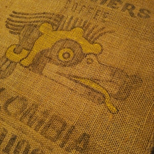 May include: A brown burlap sack with a yellow and black eagle design and the text "MINN.  CO-OP.  CREAMERIES" printed on the surface.