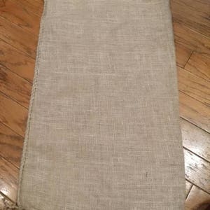 May include: A large, natural burlap sack with a rough, woven texture. The sack is empty and has a frayed edge.