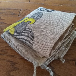May include: A folded burlap sack with a yellow and black design. The sack is made of natural fibers and has a rough texture.