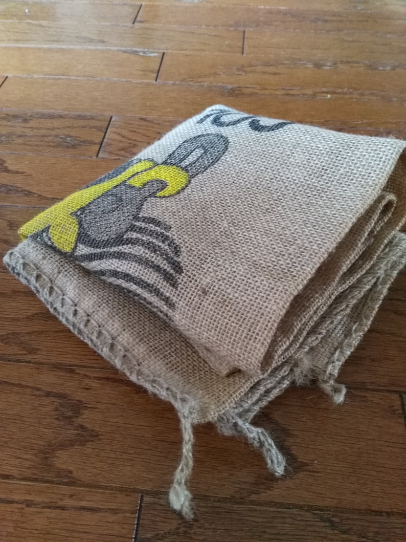 May include: A folded burlap sack with a yellow and black design. The sack is made of natural fibers and has a rough texture.