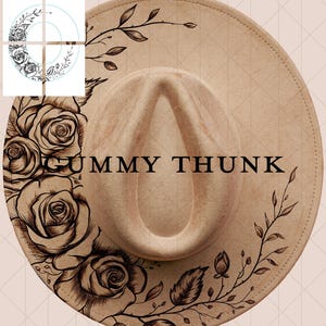 May include: A beige fedora hat with a wide brim, decorated with a dark brown floral and leaf pattern. The text "GUMMY THUNK" is printed on the crown. The hat has a traditional teardrop crown and a decorative band.