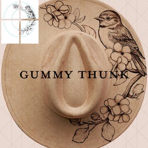 Puede incluir: Sombrero fedora color beige con diseño de pájaro y flores. El sombrero presenta una ilustración detallada de un pájaro posado en una rama con flores. El texto "GUMMY THUNK" está impreso en el sombrero.