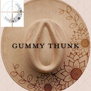 May include: A beige fedora hat with a wide brim, decorated with brown sunflower and leaf patterns. The text "GUMMY THUNK" is printed in black across the front. A fashionable hat.