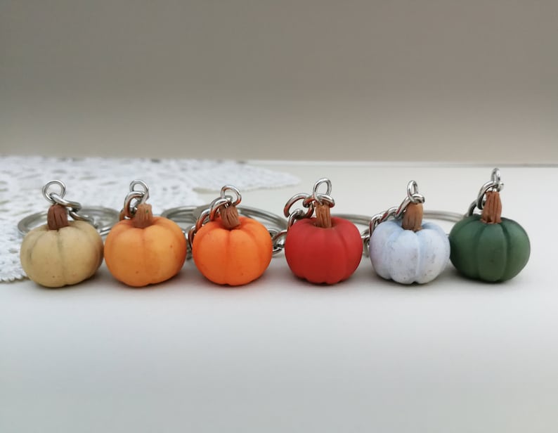Puede incluir: Seis llaveros de calabaza en miniatura de varios colores, incluyendo beige, naranja, rojo, blanco y verde. Los llaveros est&aacute;n hechos de arcilla polim&eacute;rica y tienen un anillo de metal plateado.