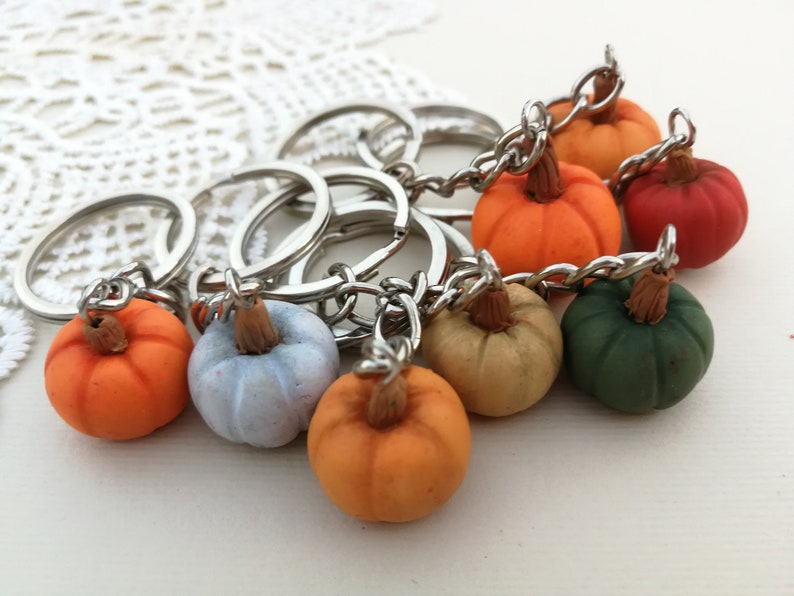 Puede incluir: Un conjunto de ocho llaveros de calabaza en miniatura. Las calabazas est&aacute;n hechas de arcilla polim&eacute;rica y vienen en una variedad de colores, incluyendo naranja, verde, azul y marr&oacute;n. Cada calabaza tiene un llavero plateado.