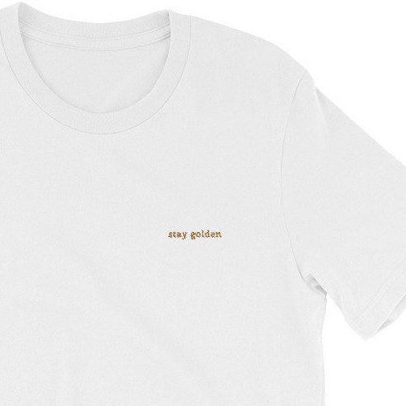 White short sleeve tee with the phrase Stay Golden embroidered in gold thread.