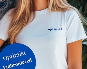 永遠の楽観主義者に！「Optimist」刺繍入り半袖ユニセックス T シャツ。刺繍入り T シャツ。刺繍入りシャツ。