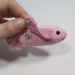 May include: A pink crocheted bunny with black eyes and a silver snap closure on the ear.