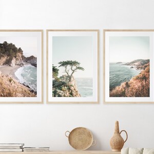 May include: Set of three framed coastal landscape photographs. The first image shows a rocky coastline with a small beach and turquoise water. The second image features a lone tree on a cliff overlooking the ocean. The third image shows a panoramic view of a coastline with a sandy beach and blue water.