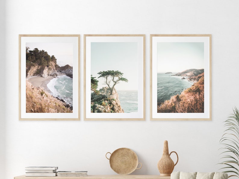 May include: Set of three framed coastal landscape photographs. The first image shows a rocky coastline with a small beach and turquoise water. The second image features a lone tree on a cliff overlooking the ocean. The third image shows a panoramic view of a coastline with a sandy beach and blue water.