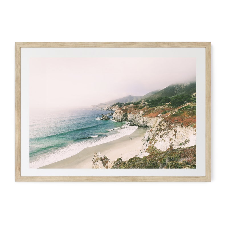 Peut inclure: Impression d'un paysage c&ocirc;tier avec plage, mer et falaises. La photographie est encadr&eacute;e dans un cadre en bois clair. La mer est turquoise et les falaises sont un m&eacute;lange de blanc et de brun. Le ciel est couvert.