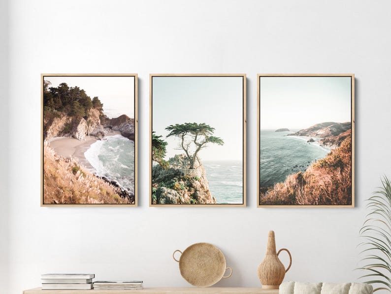 May include: Three framed landscape photographs of a coastal scene with a rocky shoreline, ocean waves, and a lone tree on a cliff. The photos are in a muted color palette with a vintage feel.