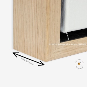 May include: Close-up of a wooden frame with a 1.5 inch / 38 mm width. The frame has a 0.2 inch / 5 mm gap between the frame and the canvas for a 3D look. The frame is light brown with a wood grain pattern.